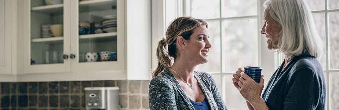 Mother and daughter having coffee in kitchen