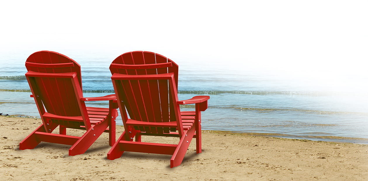 Two empty red chairs on a tropical sandy beach with ocean.